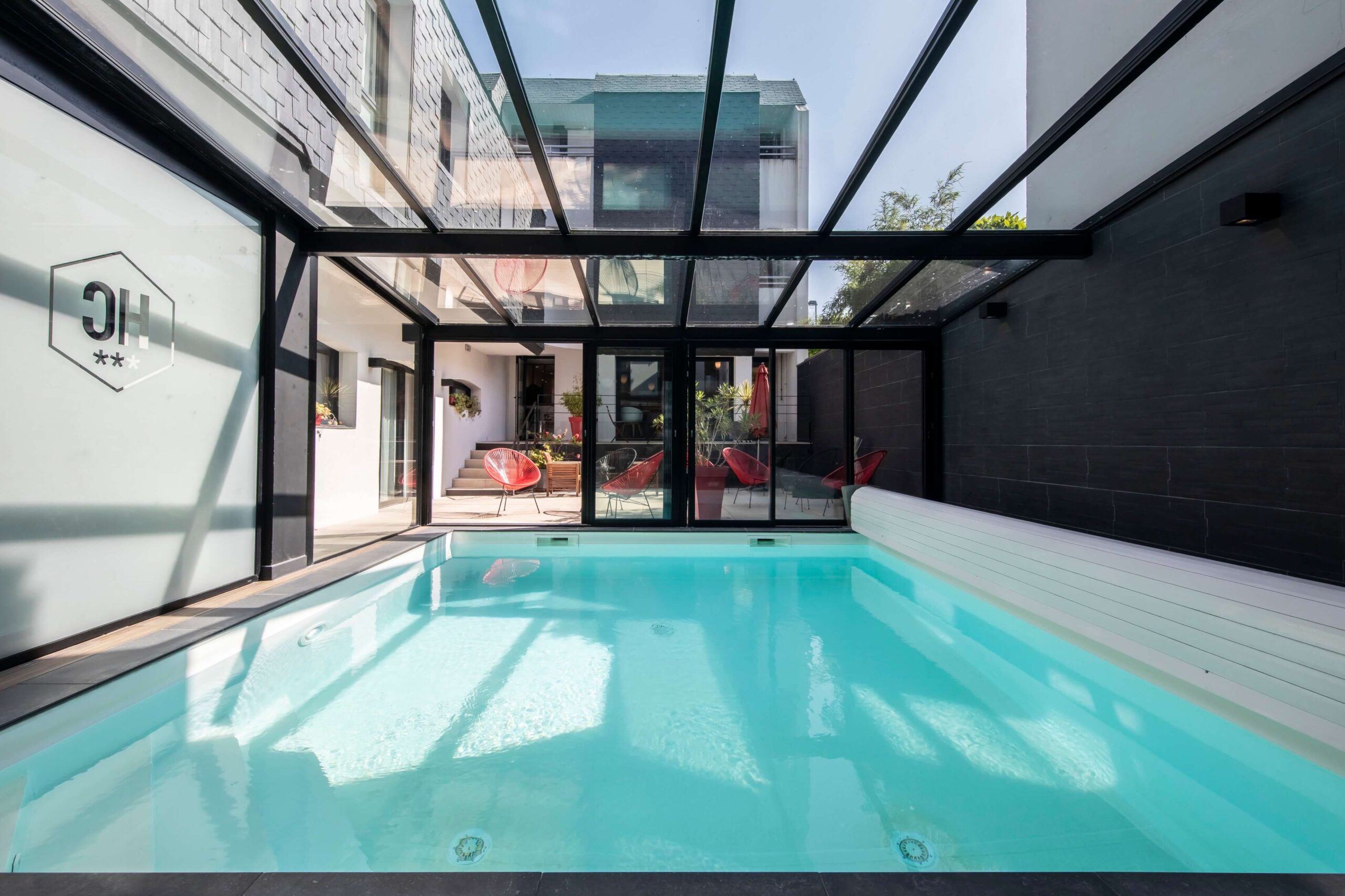 Piscine de l'hôtel Le Cornouaille, couvert et chauffée sous une belle verrière ensoleillée.