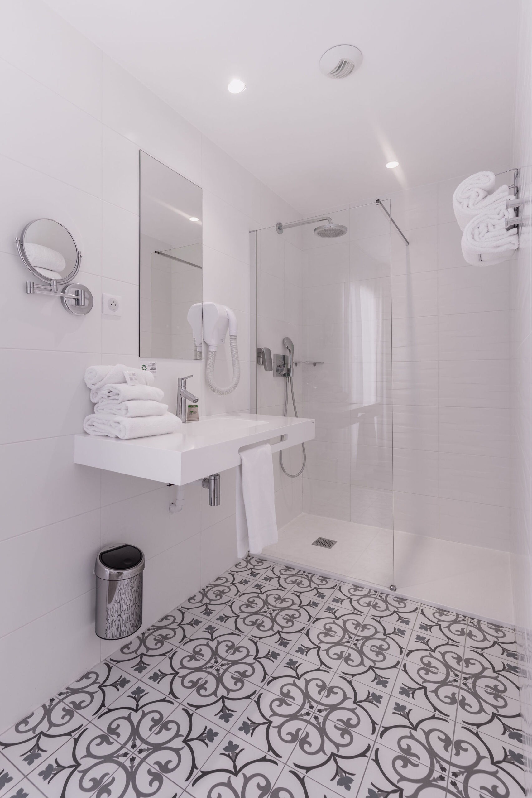 Salle de bain moderne et lumineuse de la chambre triple du Cornouaille Hôtel, équipée d'une douche à l'italienne et de serviettes soigneusement disposées.